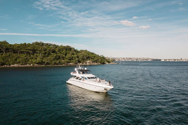 Luxurious yacht cruising near a lush island under a clear blue sky.