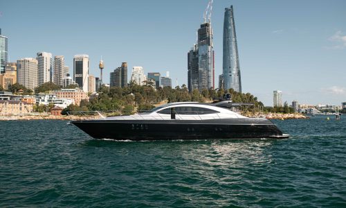 Side profile of My Privacy luxury yacht by AO Cruises cruising past the Sydney city skyline on a sunny day.
